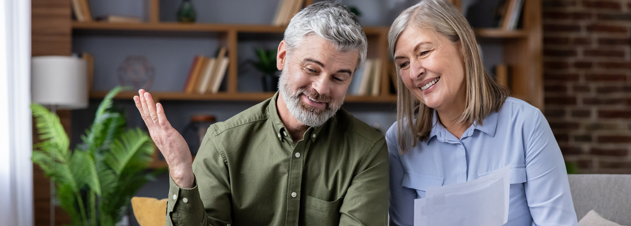 Man en vrouw bekijken financiele situatie op de laptop vanuit de huiskamer op een bank