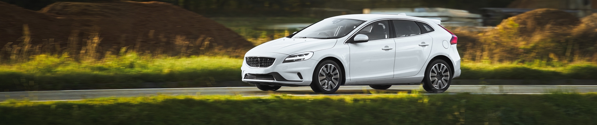 Een witte auto wat aan het rijden is in een beboste omgeving